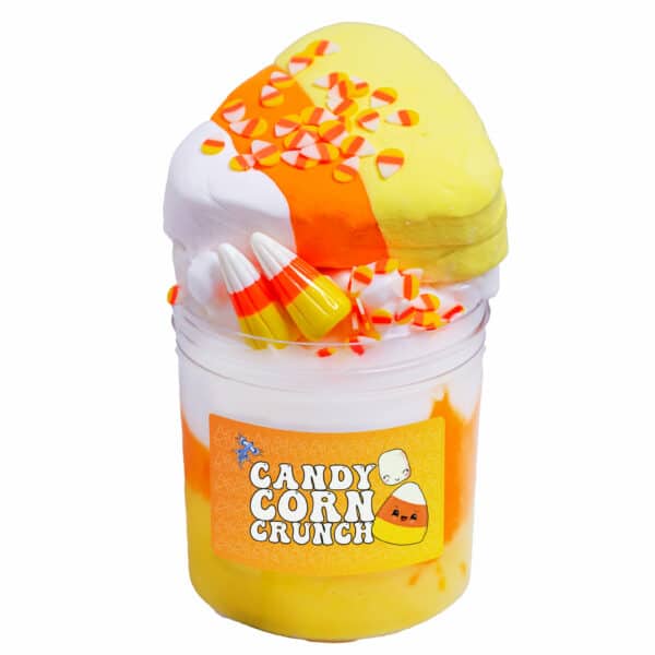 A clear jar is layered with yellow, orange, and white slime behind a label that says Candy Corn Crunch Slime. The slime is topped with a large clay candy corn, two realistic resin candy corn charms, and a generous amount of fimo candy corn sprinkles. Styrofoam mini marshmallows are visible below the toppings, mixed into the white layer of slime.