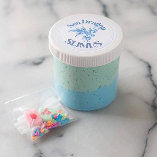 a jar of blue and green candy heart crush slime with a baggie of charms and sprinkles from Sea Dragon Slimes