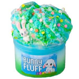 A jar of fluffy bright green, blue, and white cloud slime is piled high and topped with colorful funfetti sprinkles and a cute Easter bunny charm. The label reads Bunny Fluff Slime.