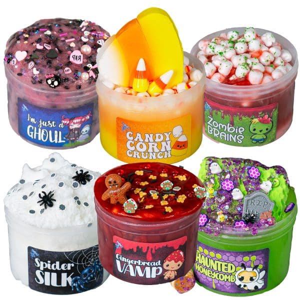 Six cute Halloween slimes are lined up with each other. A pink and black slime named I'm Just a Ghoul, an orange yellow and white slime called Candy Corn Crunch, a red and white slime called Zombie Brains, a white fluffy slime called Spider Silk, a deep red shimmer slime called Gingerbread Vamp, and a neon green and purple slime called Haunted Honeycomb.